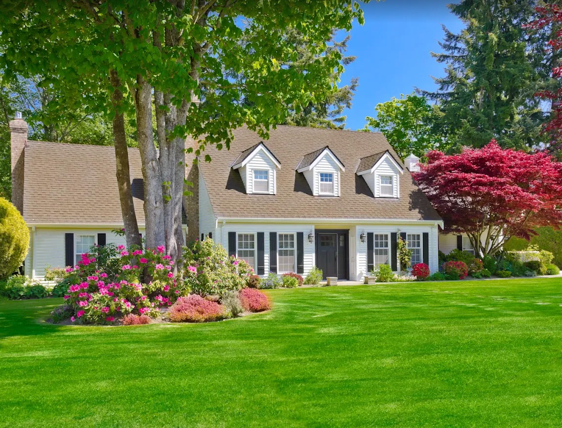 Manicured front lawn and flowering beds at a white Oakville home