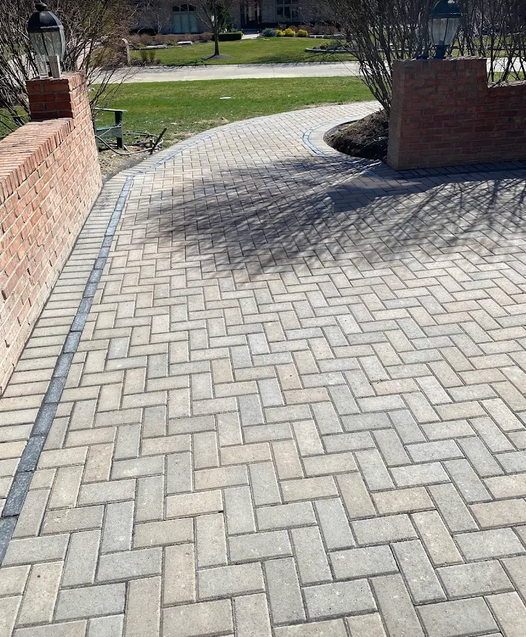 Herringbone interlock walkway with contrasting border beside brick pillars