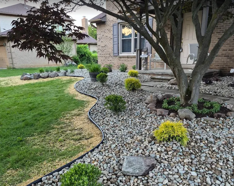 River rock bed with shrubs and steel edging beside a manicured lawn