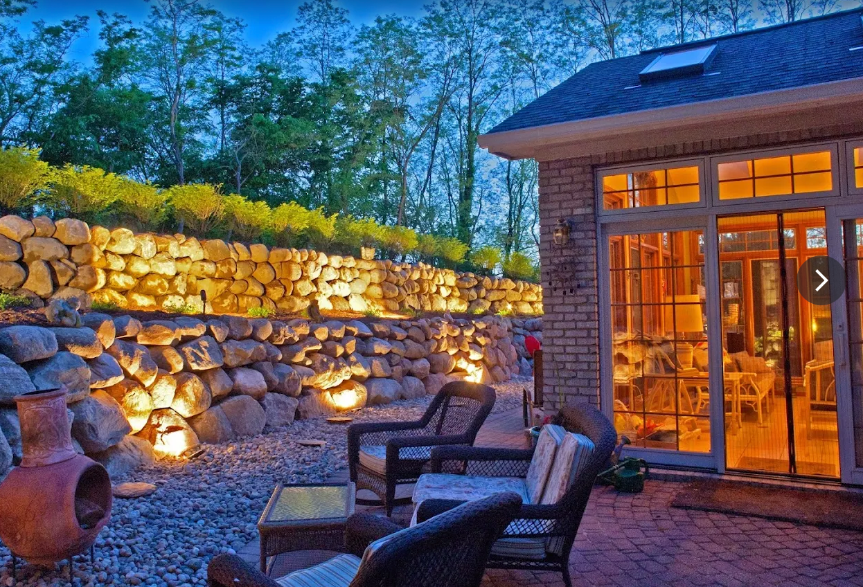 Boulder retaining walls with landscape lighting beside a paver patio