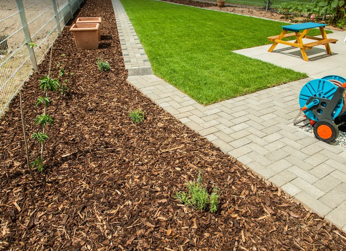 Neat sodded lawn bordered by mulch beds and paver pathways