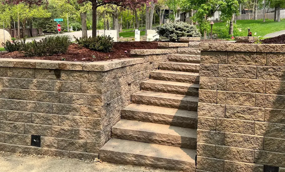 Tiered block retaining walls with stone steps and mulched planting beds