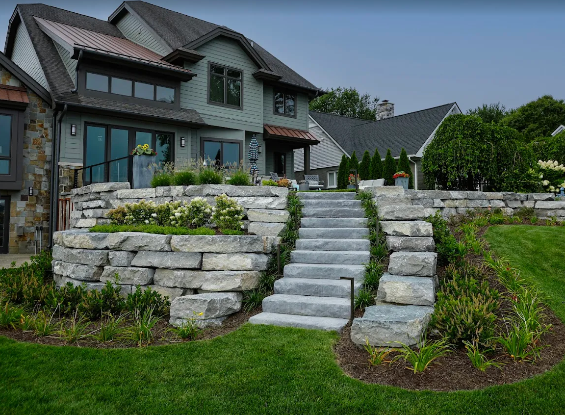 Tiered natural stone retaining walls with steps leading to a modern home