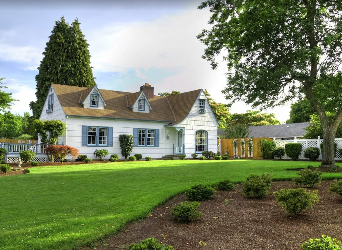 Wide green lawn and mulched beds surrounding a country-style home