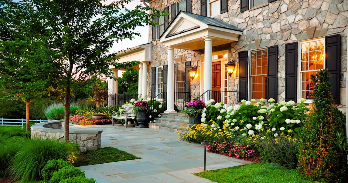 Flowering hydrangea and perennial beds framing a stone home's front walkway