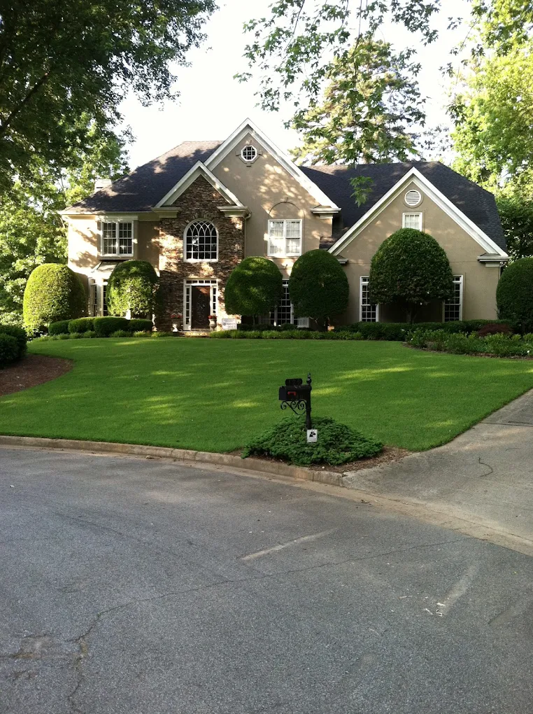 Lush established front lawn and shaped shrubs at a stone-front home